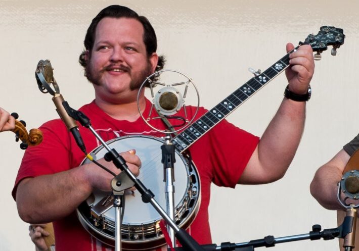 Levi playing banjo onstage at a single mic