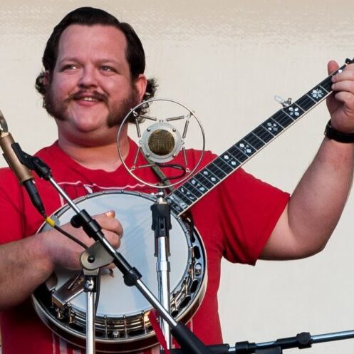 Levi playing banjo onstage at a single mic